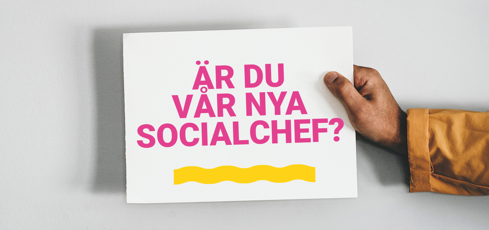 Hand som håller i en skylt med texten : Är du vår nya socialchef? 