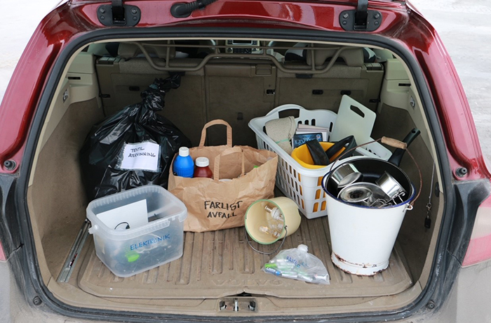 Sopor sorterade i olika behållare i bakluckan på en bil.