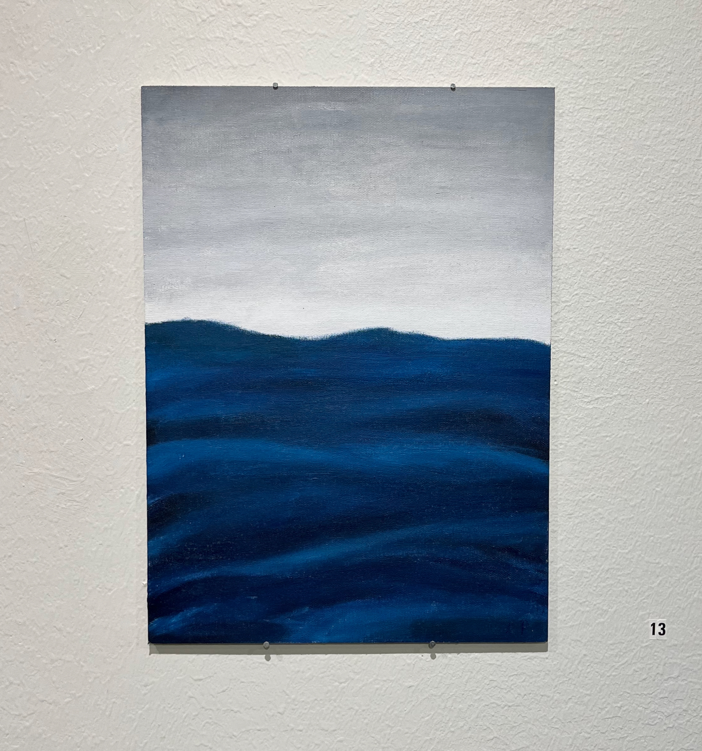 En abstrakt målning av vågig vatten och en grå himmel. Vattnet har olika djup mörkblåa nyanser. Vattnet är i rörelse, men på ett lugnt sätt. Horisonten är ljusgrå och skiftar till mörkare grå  högre upp.