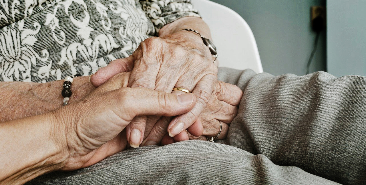 En äldre och en yngre person håller varandra i handen.