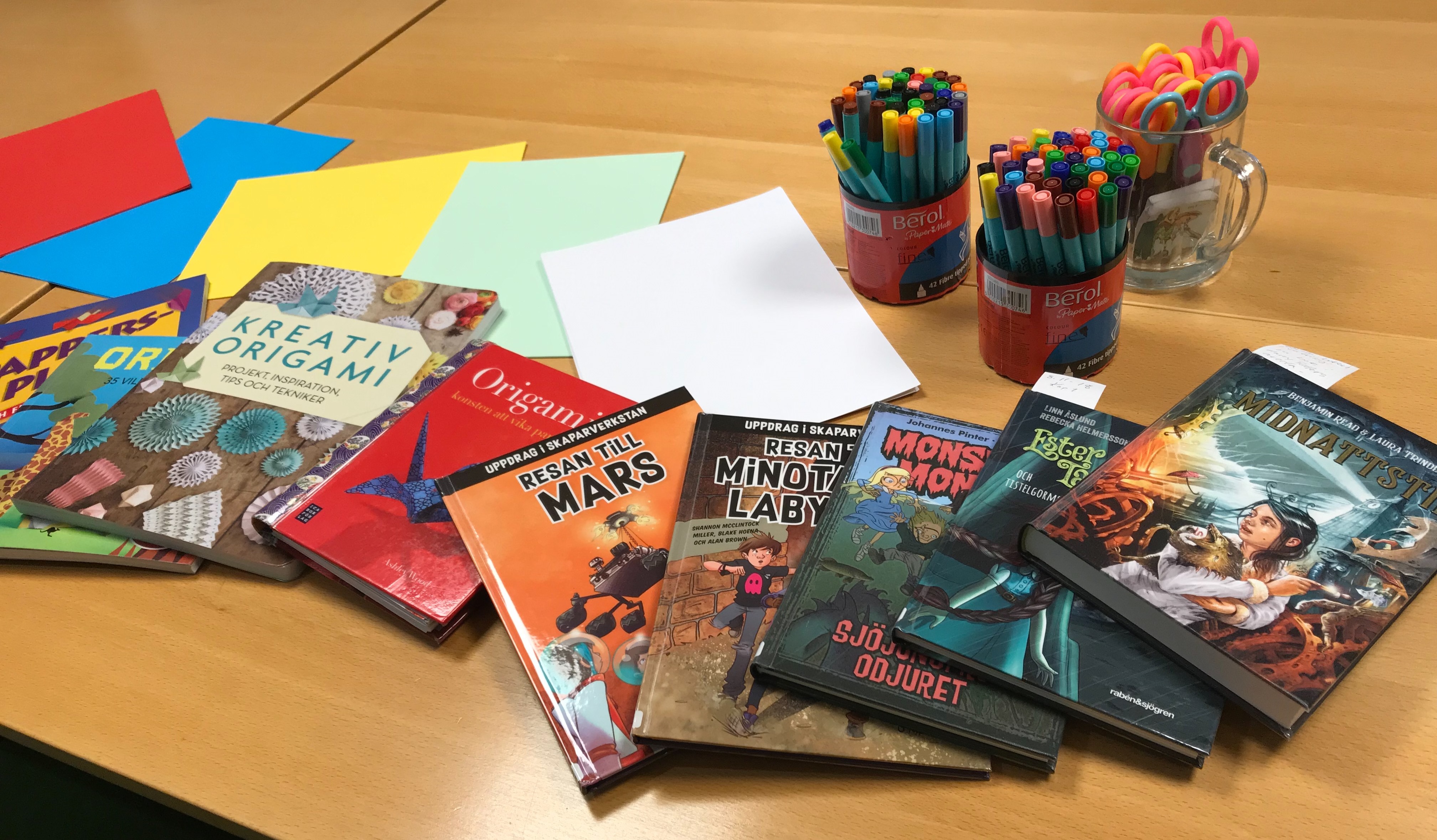 Böcker, papper och pennor i olika färger.