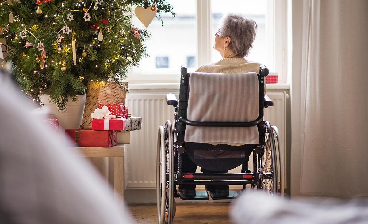 kvinna som sitter i rullstol vid en julgran