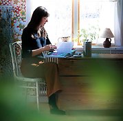 Elisabeth Embretsen sitter vid en byrå vid ett fönster och läser.