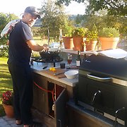 Björn Linqvist lagar mat i sitt utekök på en solig dag.