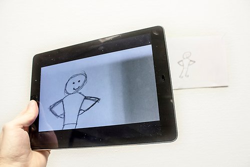 En hand håller upp en iPad med animerad bild.
