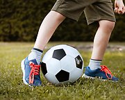 En pojkes ben sparkar på en fotboll.