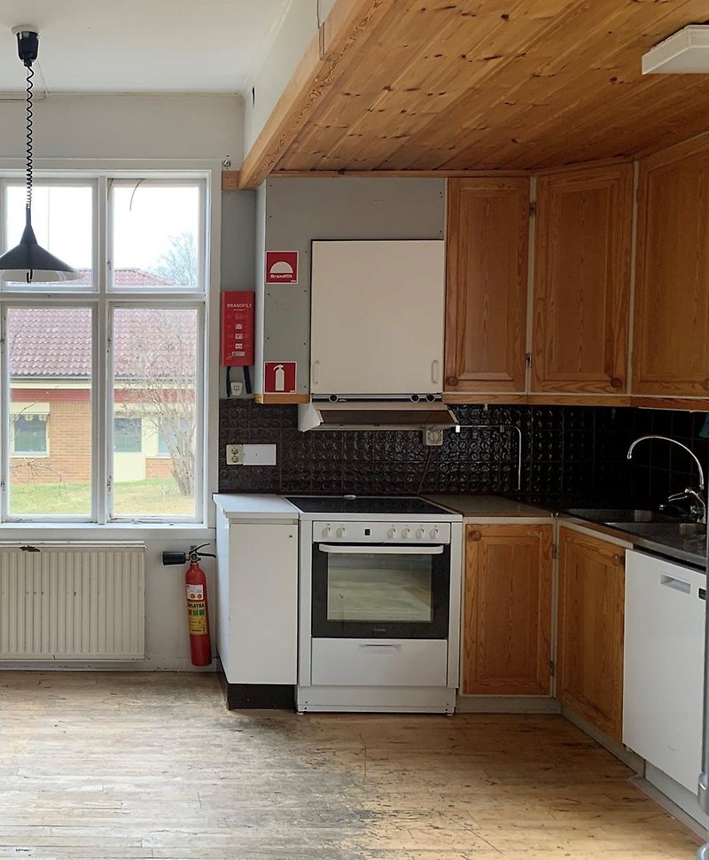Ett kök med träfärgade skåpluckor och slitet golv.