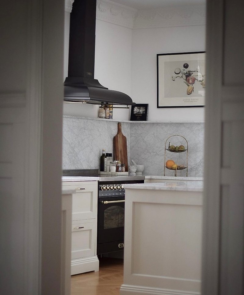 Ett modernt kök i vita, ljusgrå och svarta toner, med ett brunt, glansigt golv.