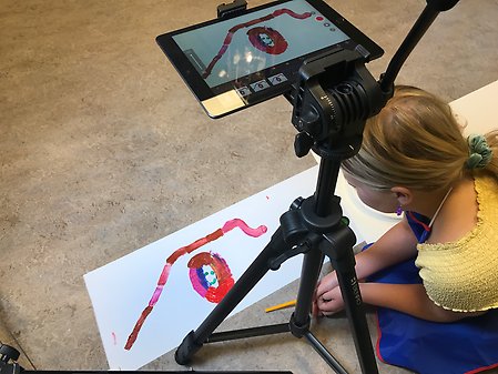 En iPad på stativ som fotograferad en bild som ett barn har målat.