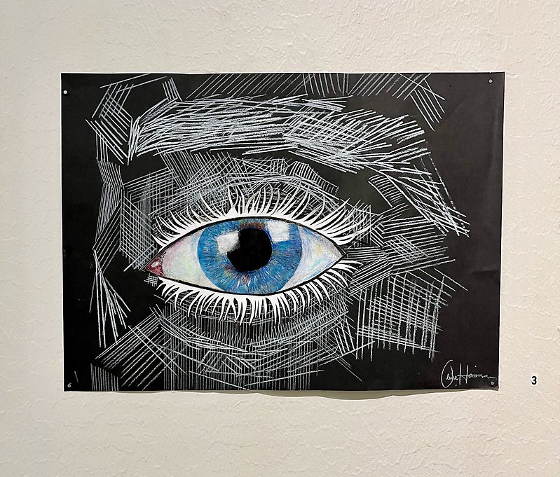 Teckning av ett blå öga med vita ögonfransar. Ansiktet som ramar in ögat är en otydlig kontour skissat med vit blyerts penna på svart papper.