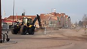 Traktorer sopar sand längs en gata.