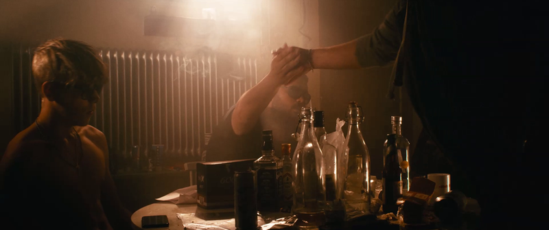 Bild från filmen #Gärdet. Ett gäng killar sitter runt ett bord i en rökig källare.