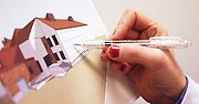 En hand som håller en penna mot en ritning av en byggnad